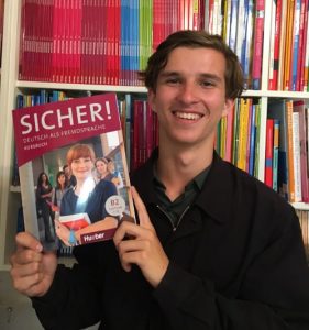 Student holding Menschen A1 German textbook
